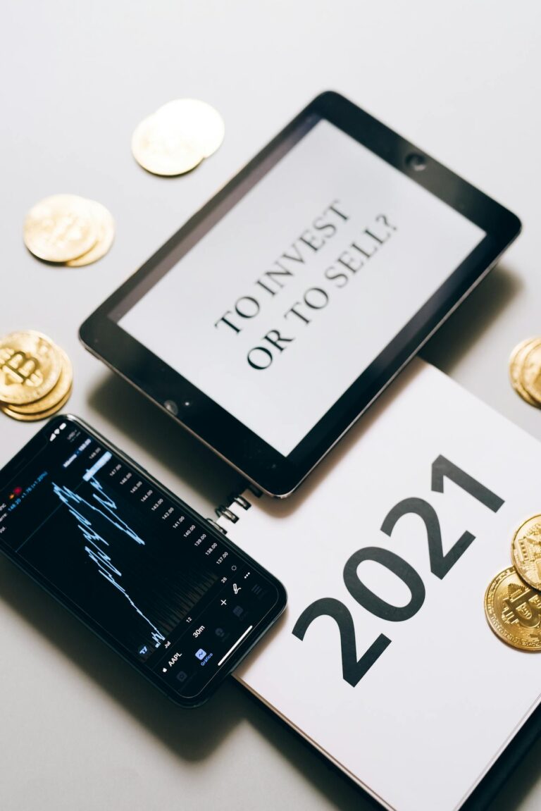 Tablet with investment question amidst bitcoins and 2021 planner. Analyze crypto trends.