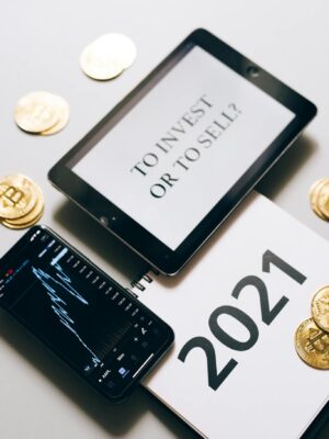 Tablet with investment question amidst bitcoins and 2021 planner. Analyze crypto trends.